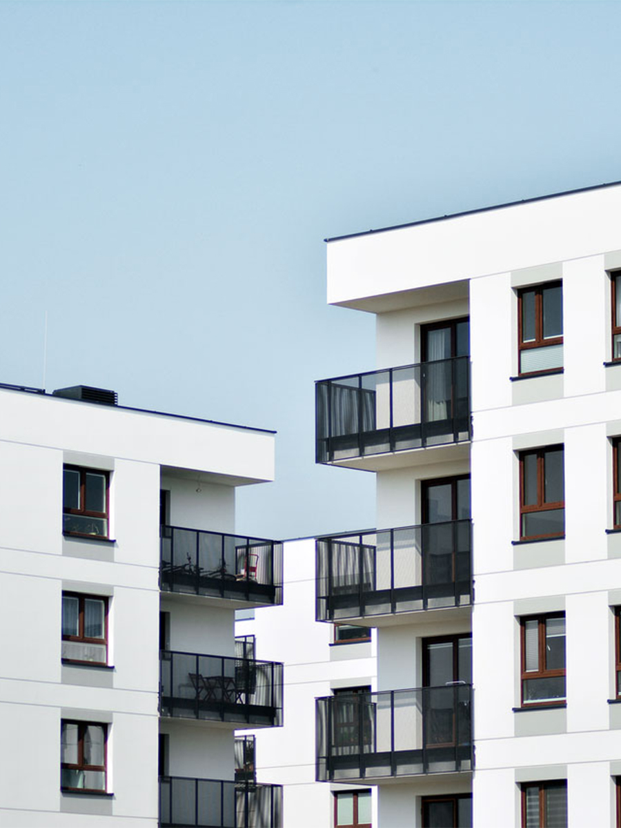 Weiße Wohnhäuser mit Balkonen stehen nebeneinander